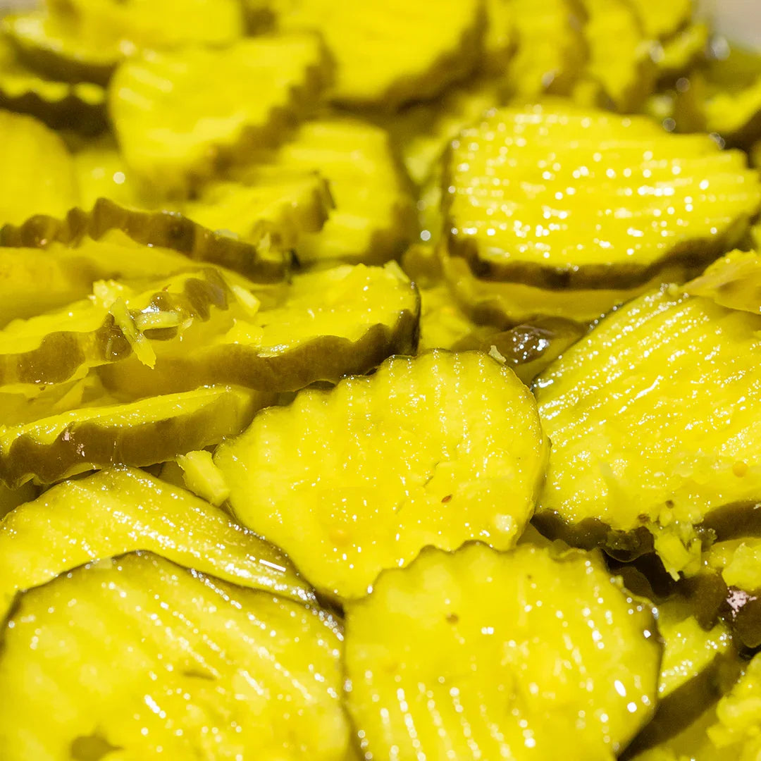Close-up of bright yellow crinkle-cut horeseradish pickles with shiny textures