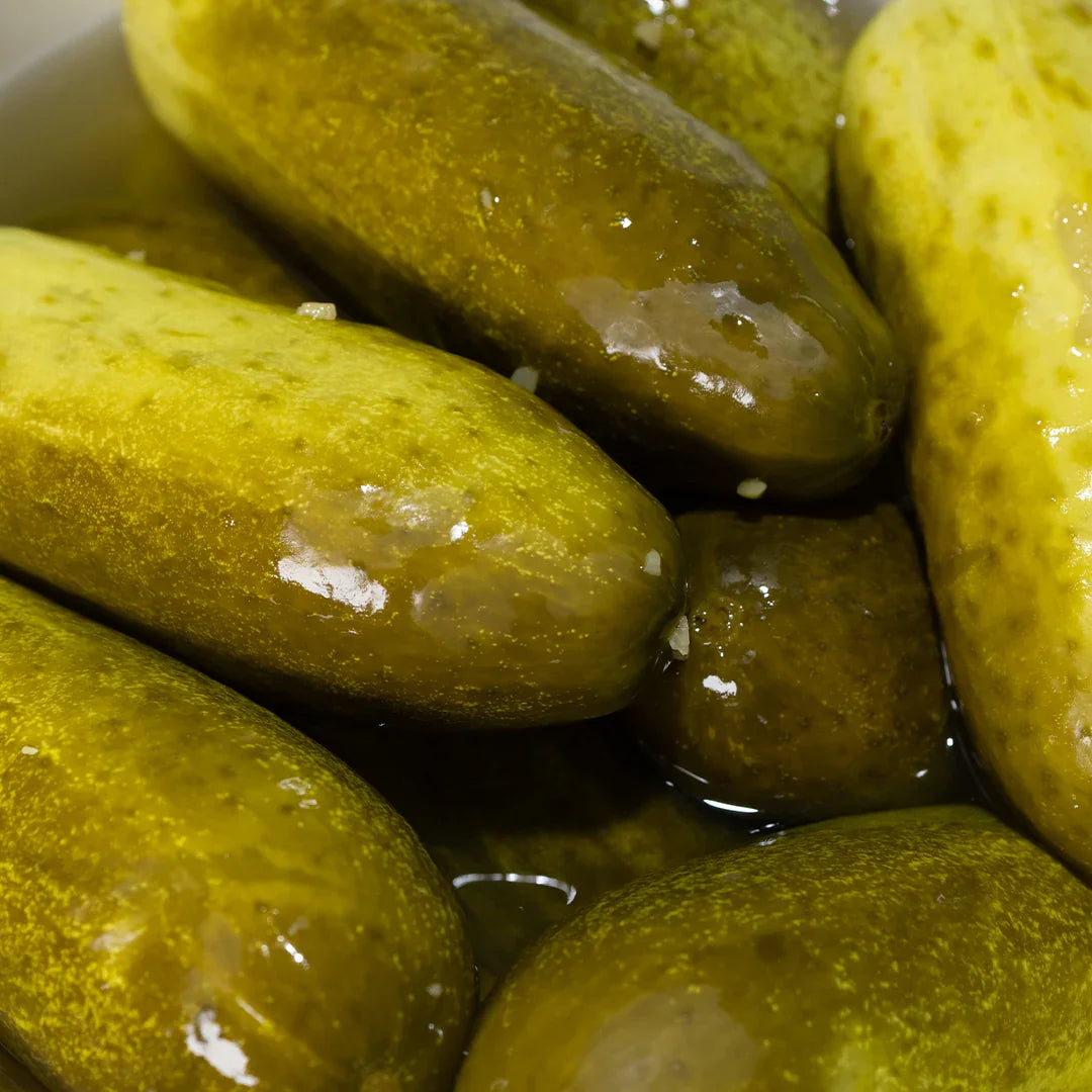 Close-up of whole uncut pickles with glossy green skin, submerged in brine