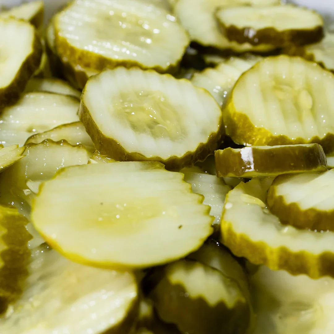 Close-up of glossy sliced ranch pickles with crinkle edges, submerged in brine