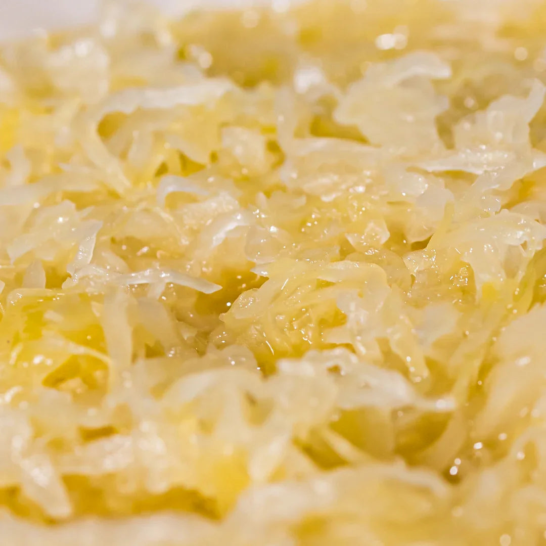 Close-up of shredded sauerkraut strands with pale color, layered texture, and moist fermented appearance