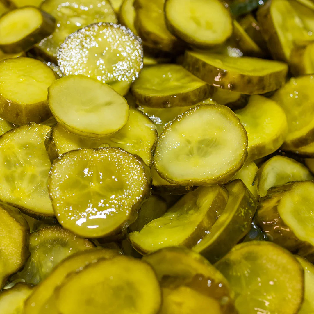 Close-up of glossy sliced sweet hotties pickles in brine with greenish-yellow color and visible texture